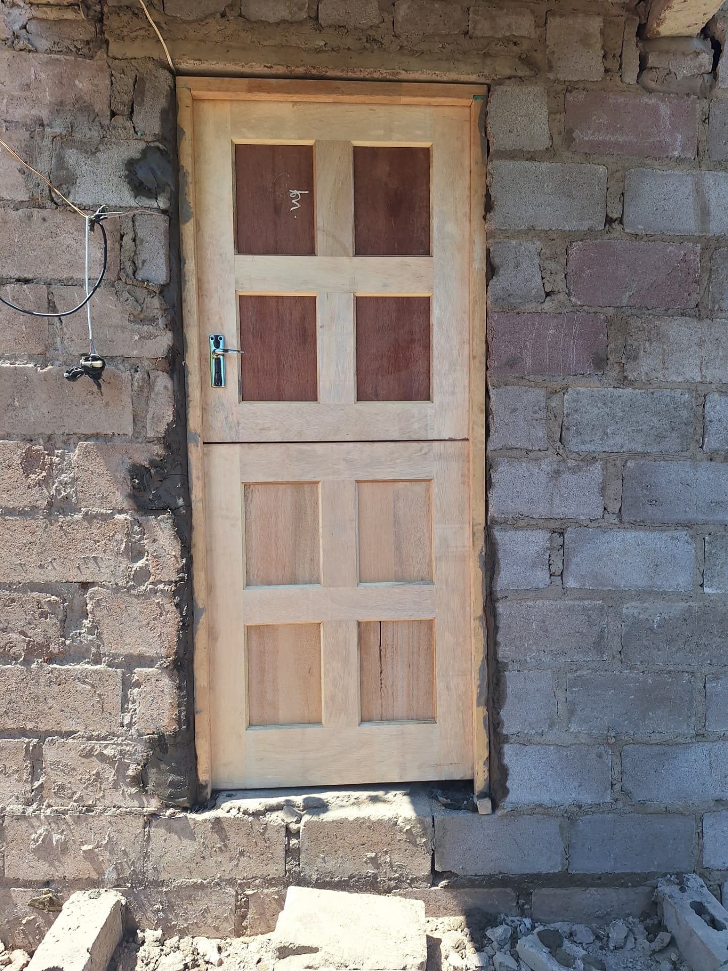 A new wooden panelled door with a transom window set into the newly built block walls