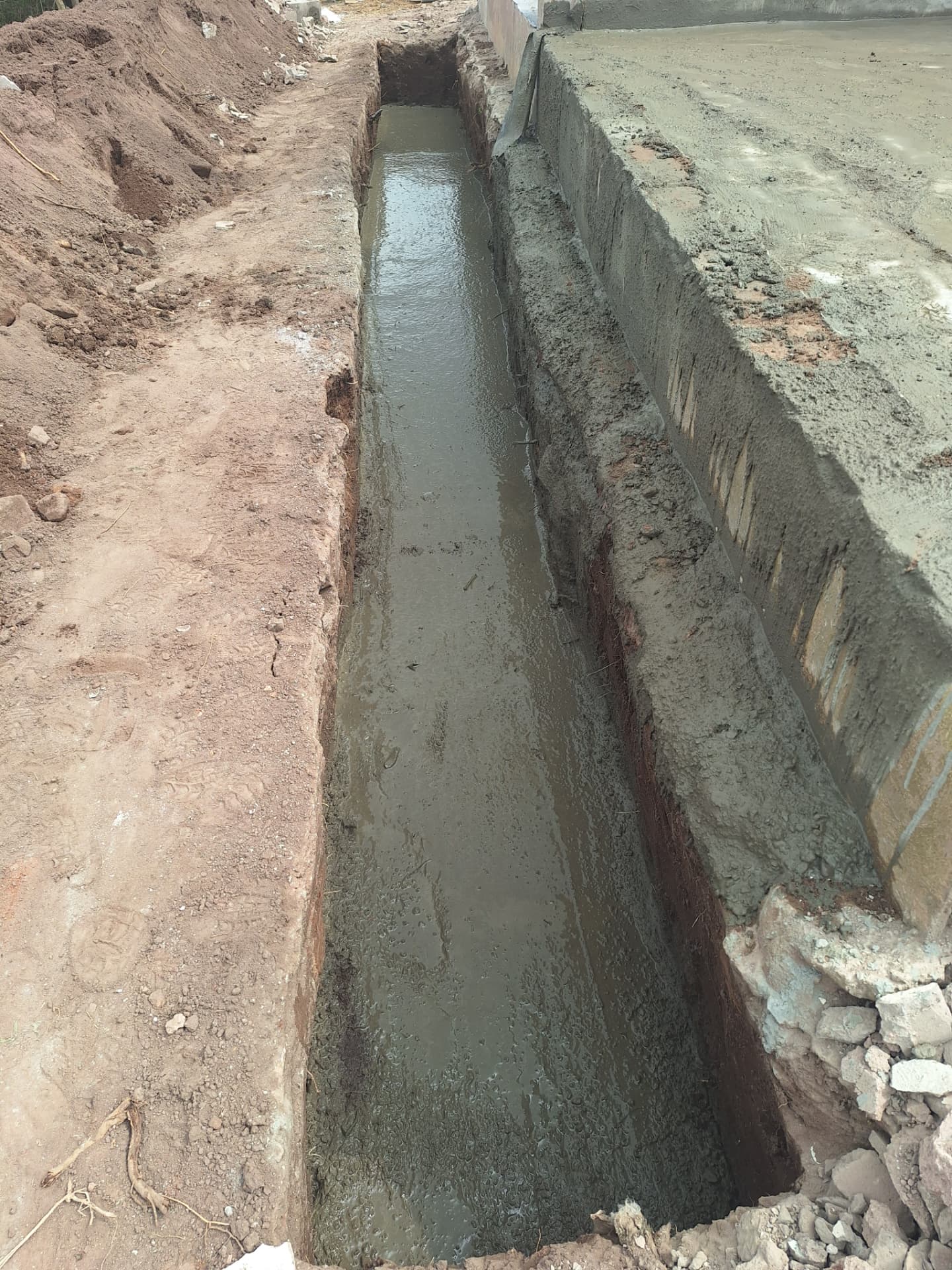 A freshly dug foundation trench filled with wet concrete at Baba Buthelezi’s home